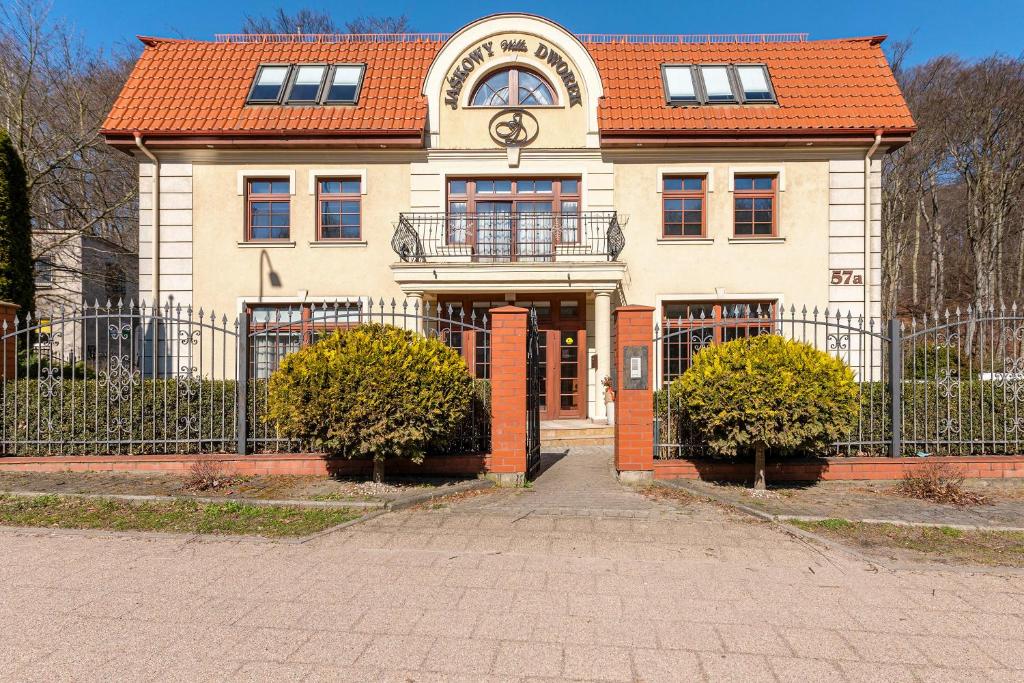Biały dom z pomarańczowym dachem i płotem w obiekcie Willa Jaśkowy Dworek w Gdańsku