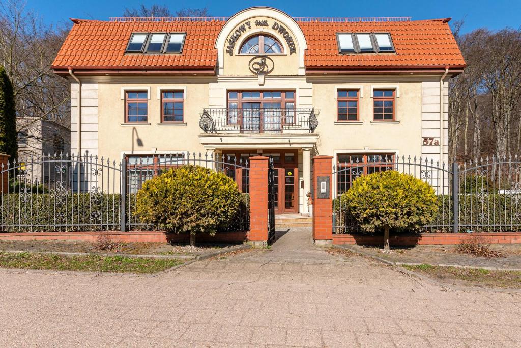 a white house with an orange roof and a fence at Willa Jaśkowy Dworek in Gdańsk