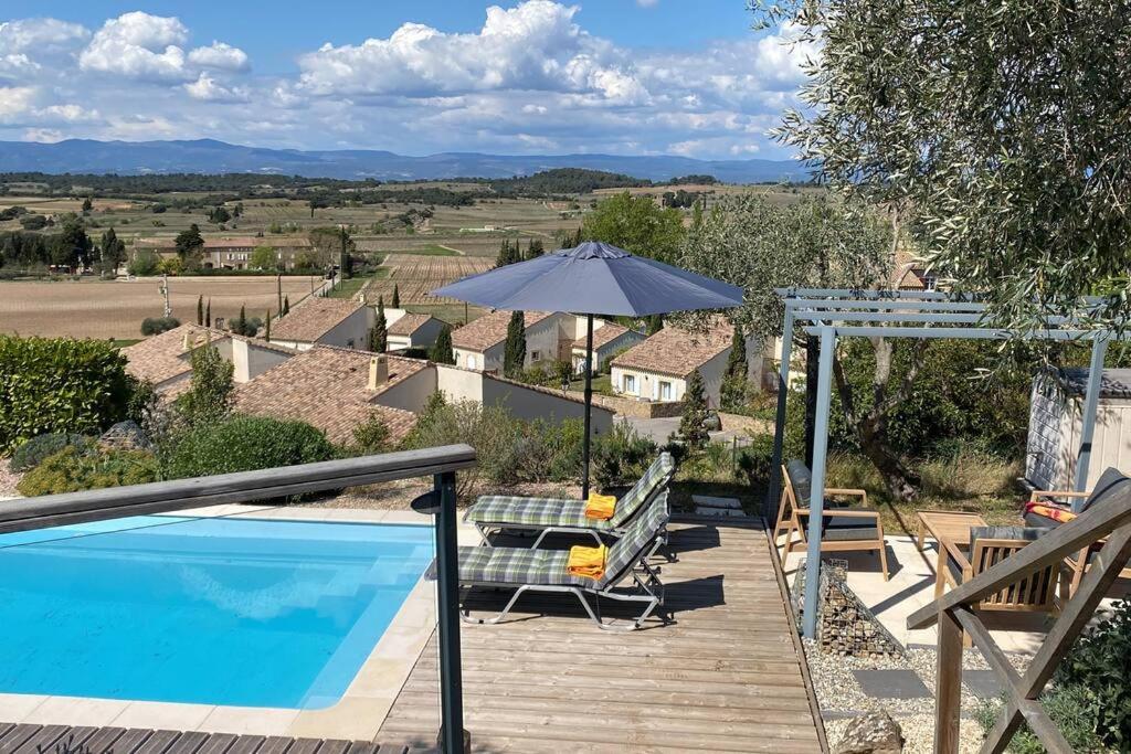 a house with a swimming pool and an umbrella at Neuve Romantique in Montbrun-des-Corbières