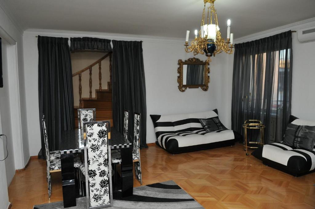 una sala de estar con muebles blancos y negros y una lámpara de araña. en Nino Duplex Apartment, en Tiflis