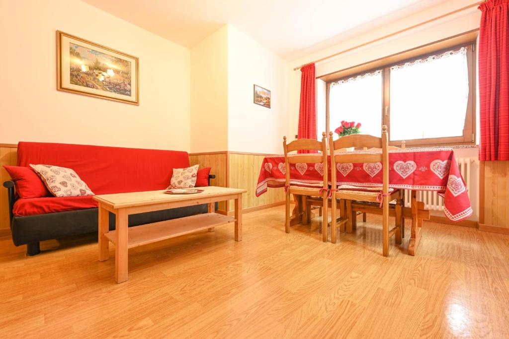 ein Wohnzimmer mit einem roten Sofa und einem Tisch in der Unterkunft Majon Fior de Bosch 1 in Campitello di Fassa