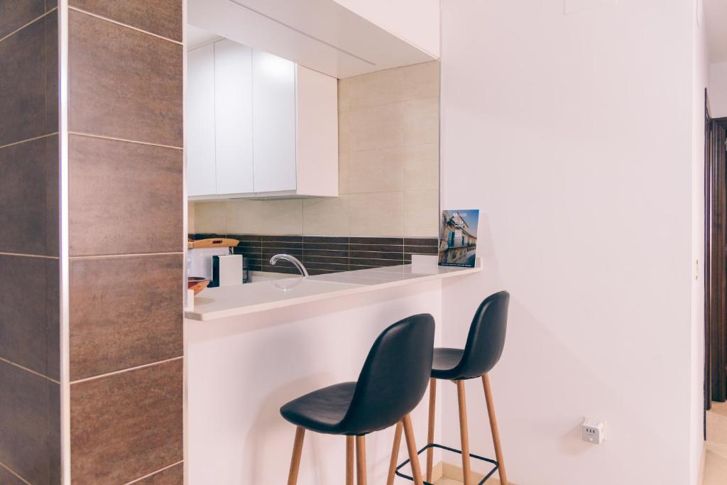 a kitchen with two black chairs and a sink at Casa Yaye Écija in Écija