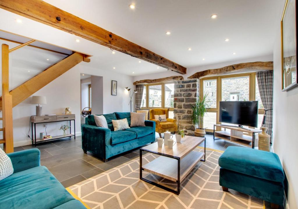 a living room with blue couches and a tv at Derwen in Llanfihangel-geneuʼr-glyn