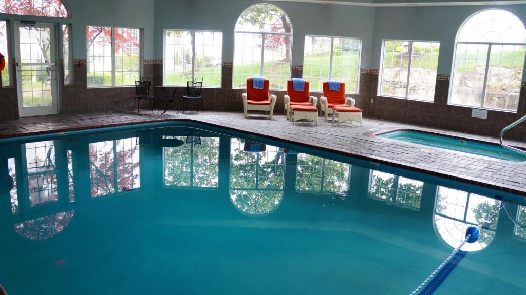uma piscina com três cadeiras e uma piscina em Hotel Grand Victorian em Branson