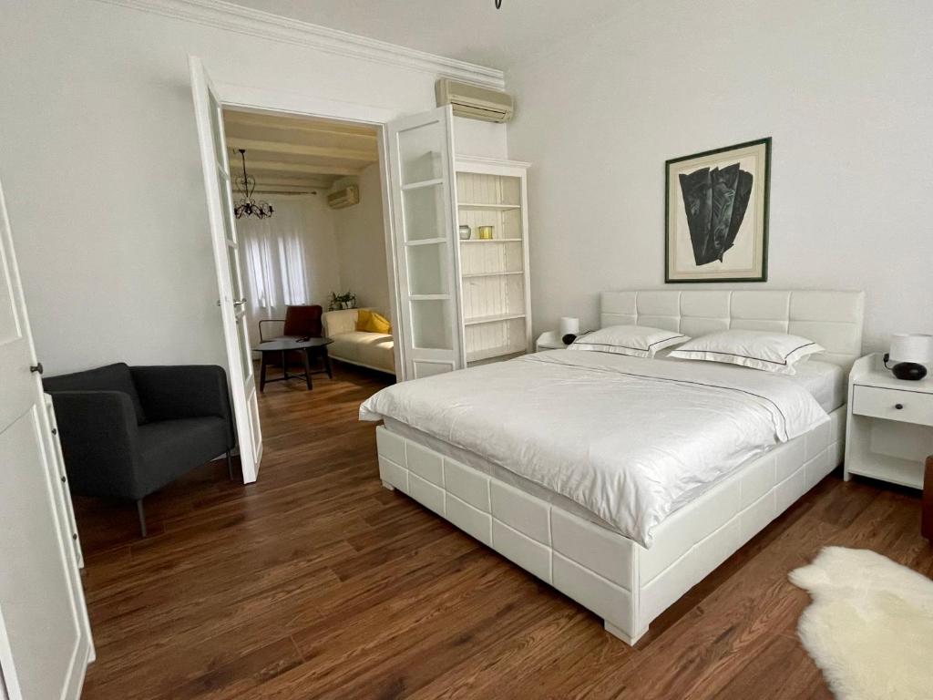 a bedroom with a white bed and a chair at Linden Korzo with balcony in Rijeka