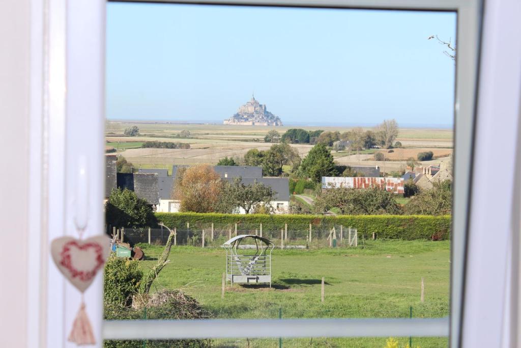 uma vista de um campo a partir de uma janela em Aux Chambres du Mont em Huisnes-sur-Mer