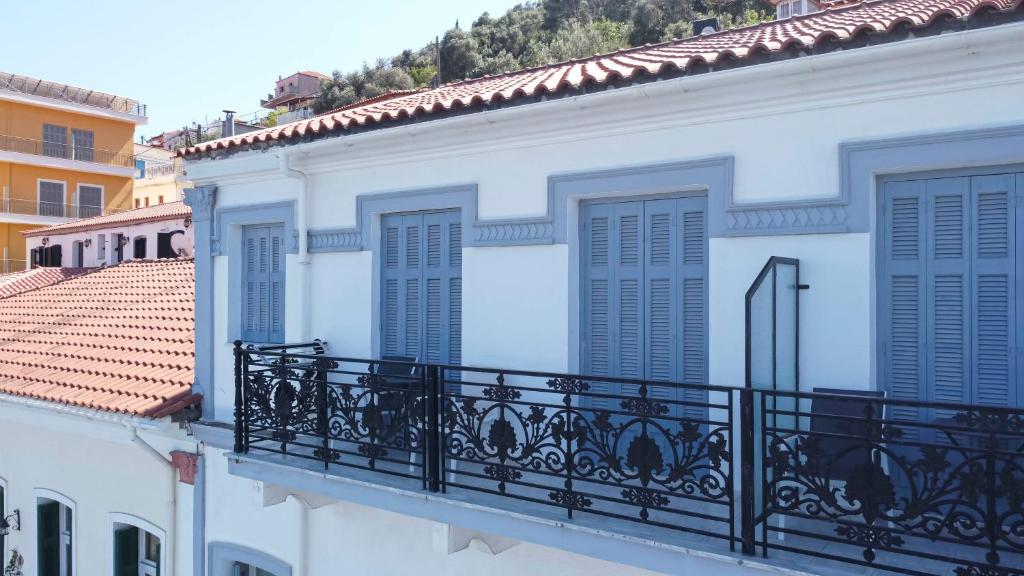 - un bâtiment blanc avec un balcon doté de volets bleus dans l&#39;établissement Leonidas Hotel, à Gythio