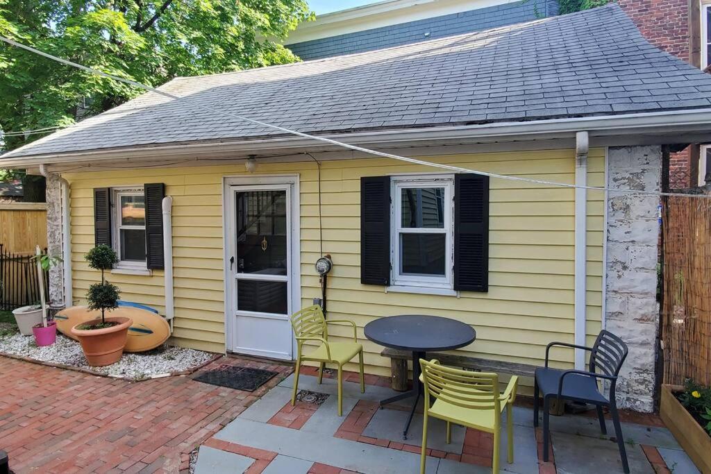 a yellow house with a table and chairs on a patio at Harvard Squares ONLY Tiny House on the Charles! in Cambridge