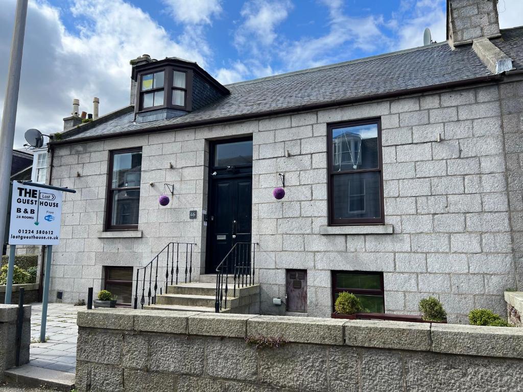 a white brick building with a black door at Lost Guest House Aberdeen in Aberdeen