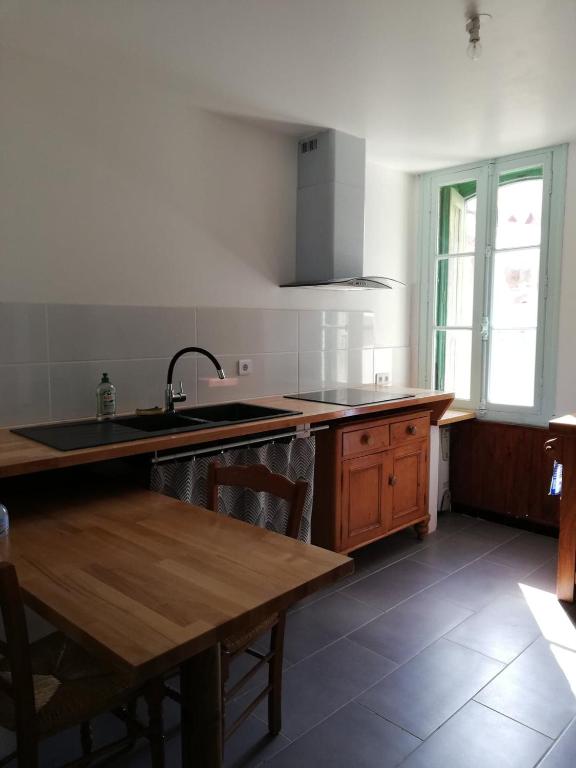 uma cozinha com um lavatório e uma mesa de madeira em T2 petite terrasse coeur de ville em Prats-de-Mollo-la-Preste