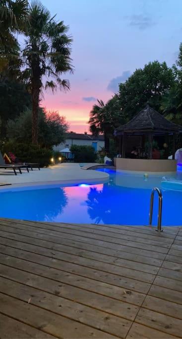 a blue swimming pool with a sunset in the background at Gite l’Oasis in Astaffort