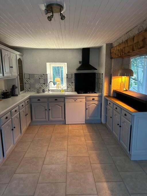 a large kitchen with white cabinets and a tile floor at Gite l’Oasis in Astaffort