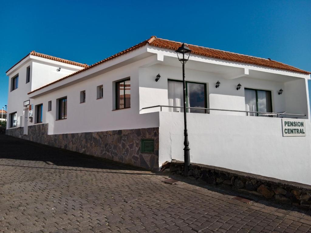 a white house with a cobblestone street at La Palma Hostel by Pension Central in Fuencaliente de la Palma