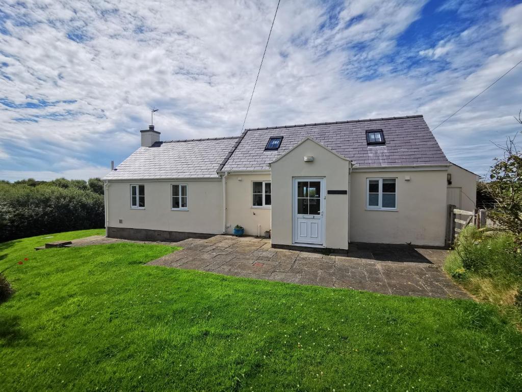 a white house with a green yard at Tan Y Ffordd in Morfa Nefyn