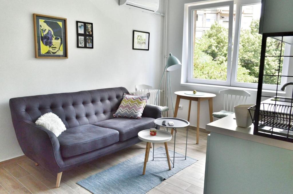 Una sala de estar con un sofá y dos mesas. en Home Apartment LUNA 1, en Skopje