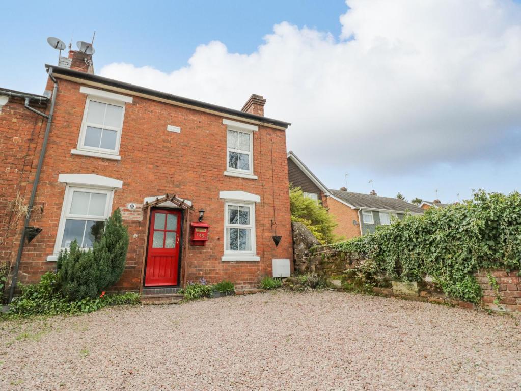 a red brick house with a red door at Dobbies Den in Bewdley