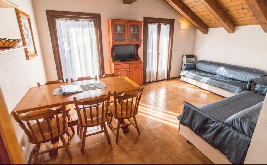 een woonkamer met een tafel en stoelen en een bank bij Residence Borgo Al Sole in Sappada