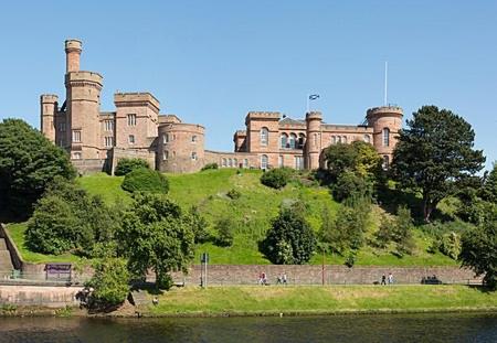 um castelo no topo de uma colina ao lado de um corpo de água em Inverness Highland Apartment em Inverness