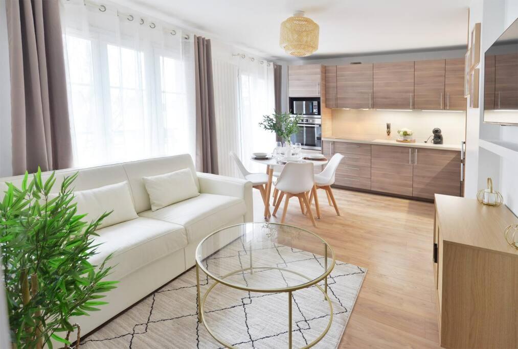 uma sala de estar com um sofá branco e uma mesa em L'Olivier Disneyland JO Paris 2024 avec Parking em Bailly-Romainvilliers