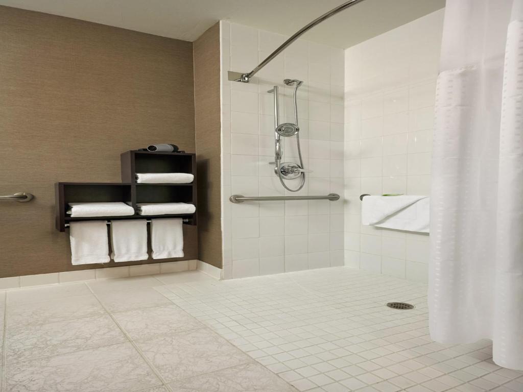 a bathroom with a shower and a toilet and towels at Holiday Inn Express & Suites Naples Downtown - 5th Avenue by IHG in Naples