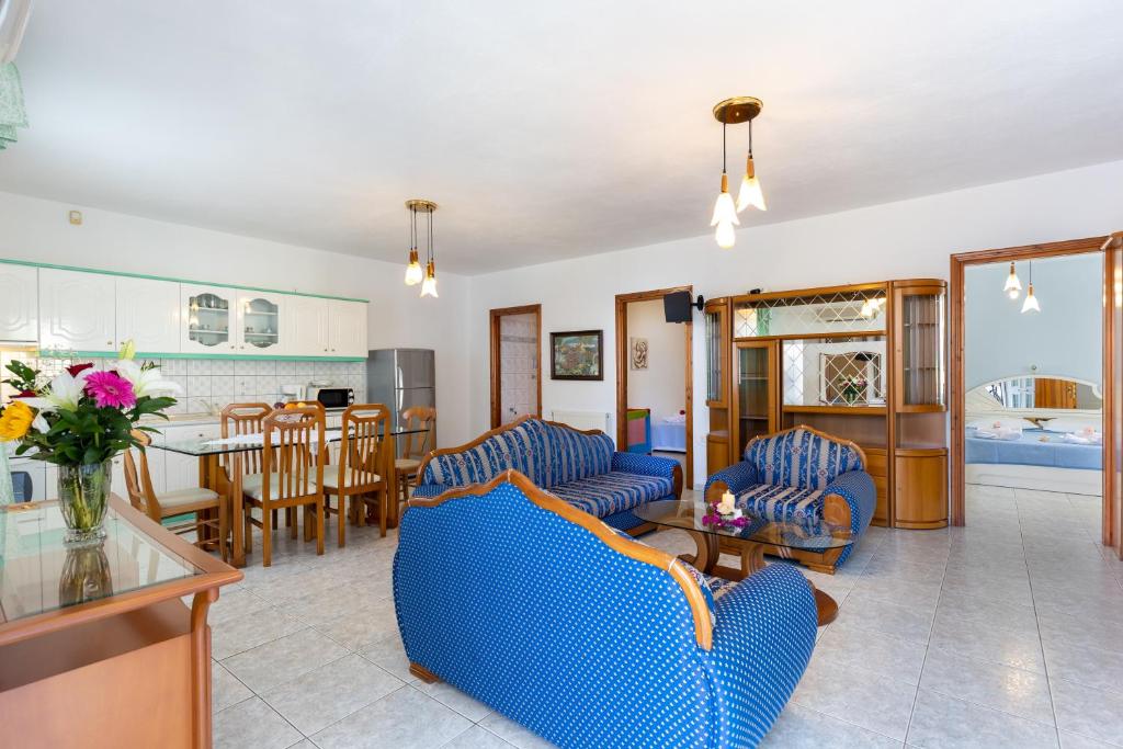 a living room with two blue couches and a kitchen at Villa Romantika in Chrysi Ammoudia