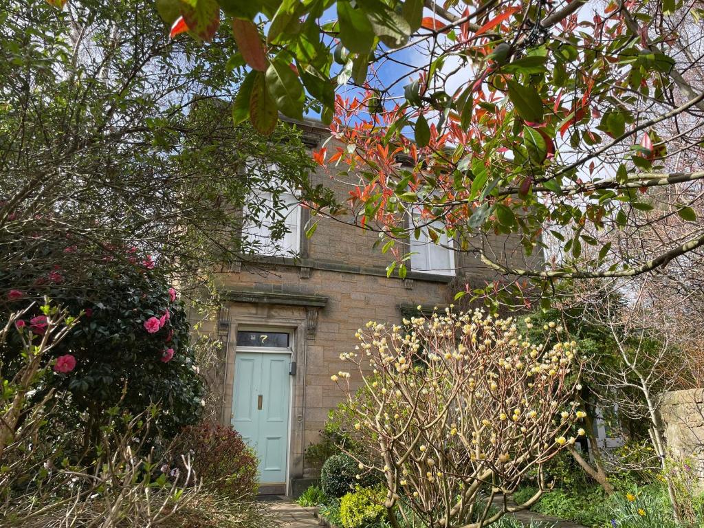 a brick house with a blue door and some flowers at Large 3 double bedroom period house with parking in Edinburgh