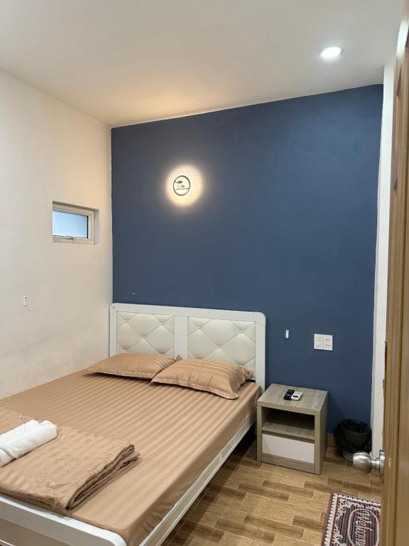 een slaapkamer met een bed met een blauwe muur bij D Home in Ho Chi Minh-stad