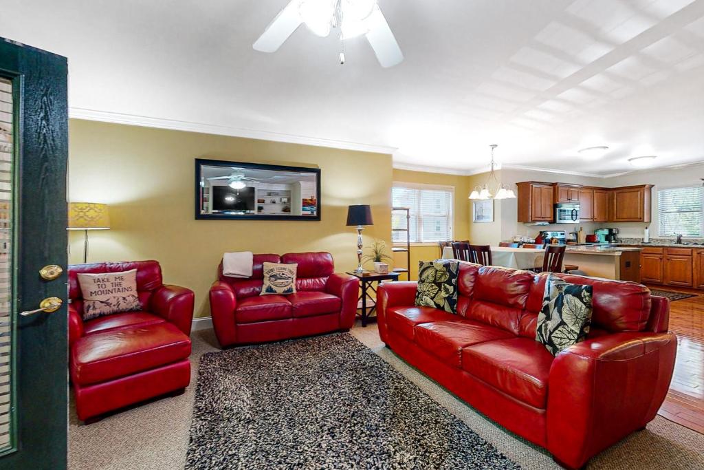 sala de estar con muebles de color rojo y cocina en Riverside Trout Cottage en Helen