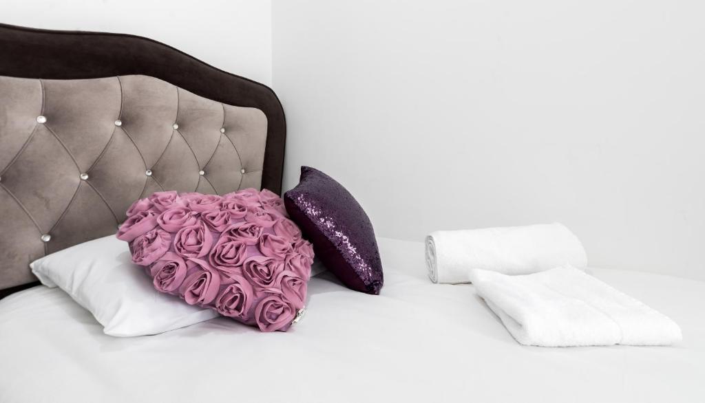 a pink pillow on a bed with purple pillows at Aldgate Flats in London