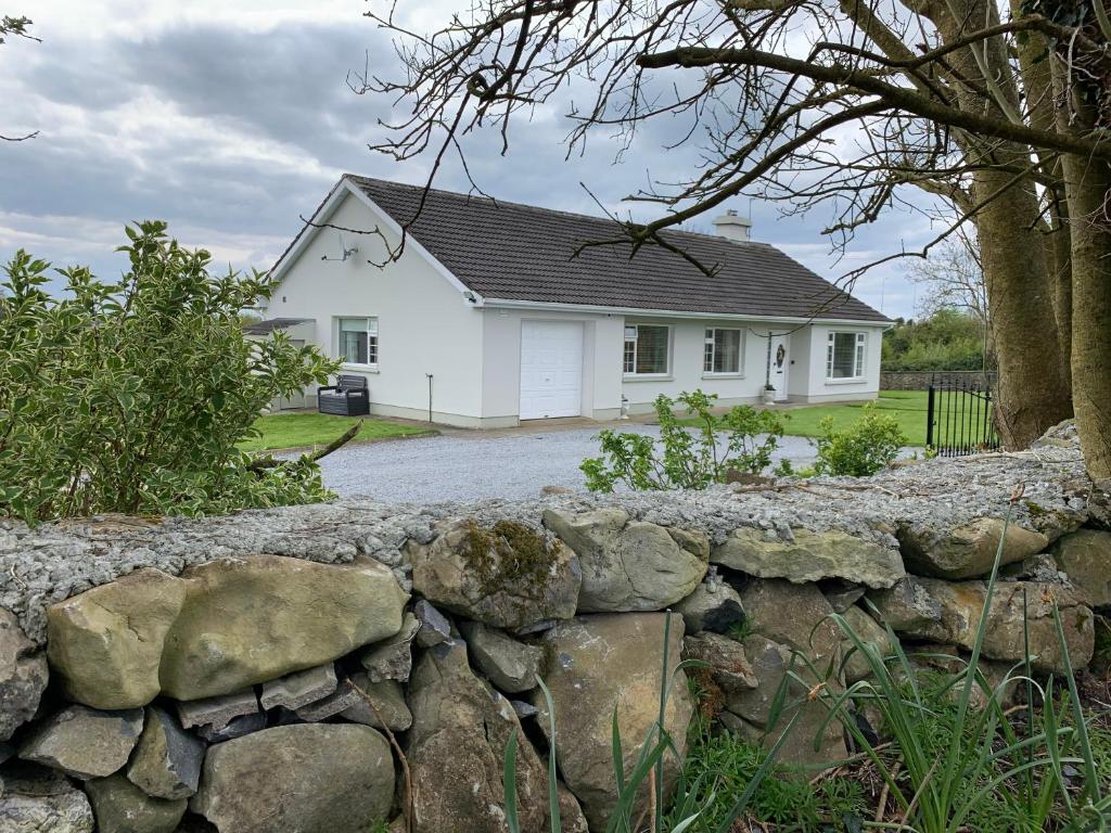 een wit huis achter een stenen muur bij Bridgeview B&B in Ennis