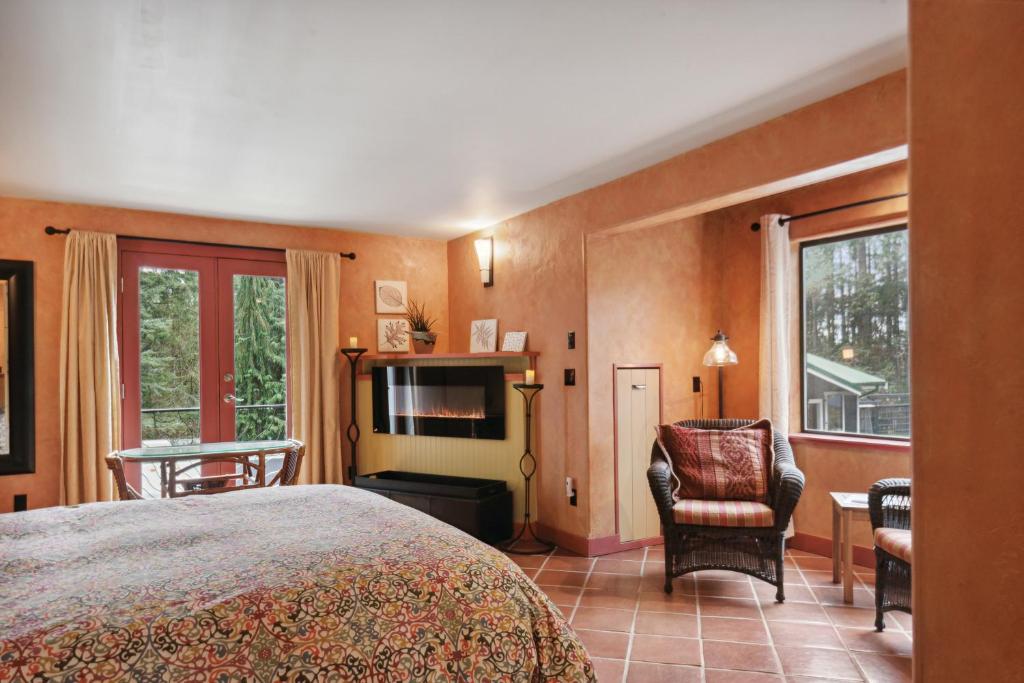 a bedroom with a bed and a tv and a chair at Salt Spring Carriage House B&B in Ganges