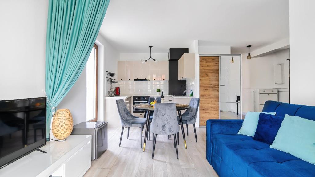 - un salon avec un canapé bleu et une table dans l'établissement STEGNA PARK C Apartamenty Piamola WiFi, à Stegna