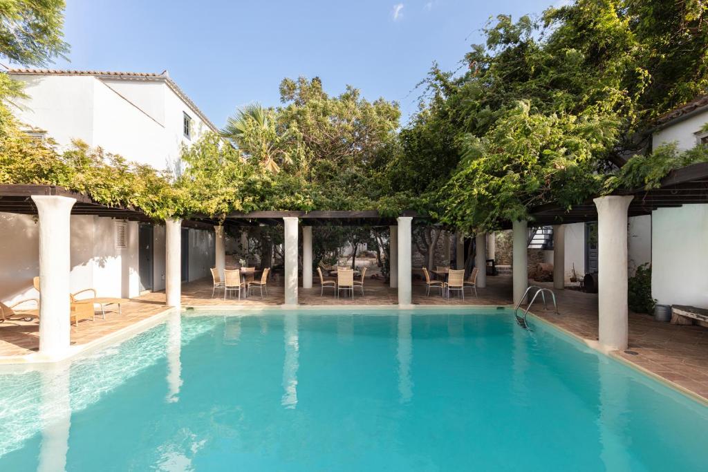 a swimming pool with trees and chairs in a house at Bratsera Boutique Hotel in Hydra