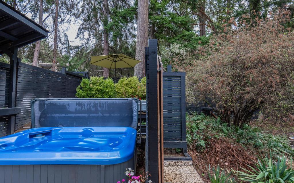 a hot tub and an umbrella in a backyard at Salt Spring Carriage House B&B in Ganges