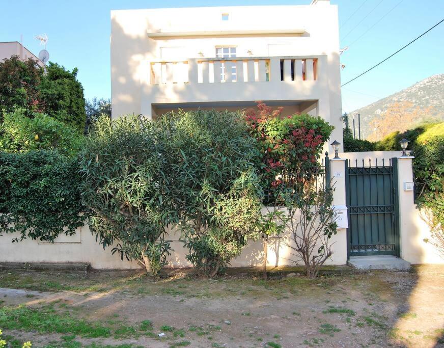 una casa bianca con un cancello e alcuni cespugli di πολυτελής εξοχική κατοικία a Nea Makri