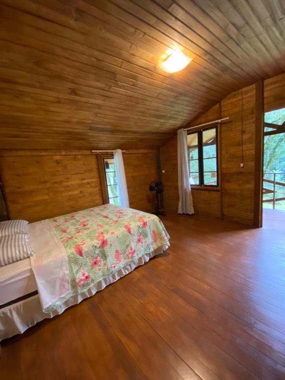 a bedroom with a bed and a wooden floor at Chalé Verdant in Canoinhas