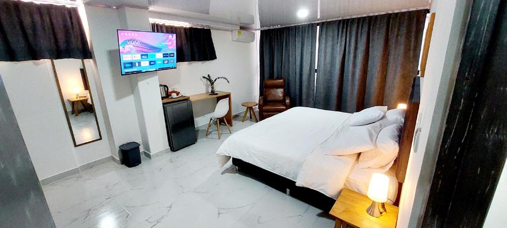 Dormitorio con cama, escritorio y TV en HOTEL A & A SANTA ALEJANDRIA, en Medellín
