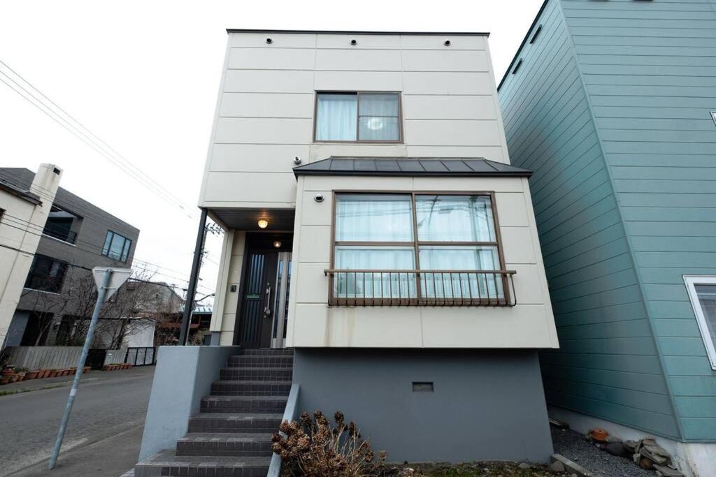 a white house with stairs in front of it at Stay In Miyashita in Asahikawa