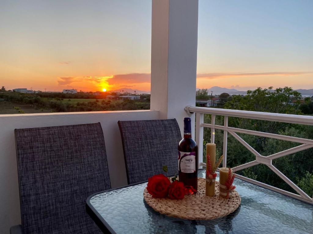 a table with a bottle of wine and flowers on a balcony at Sunset View Apartment, in the nature, at Zipari "6" in Kos