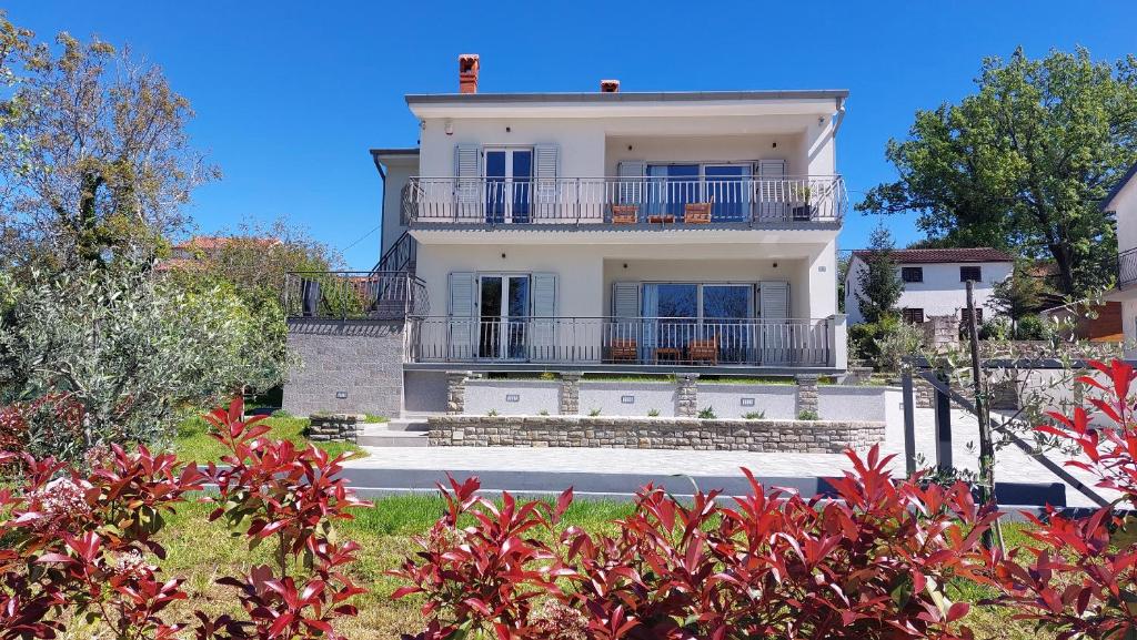 a large white house with a balcony on top at Villa Amoena with Pool and Sauna in Brtonigla