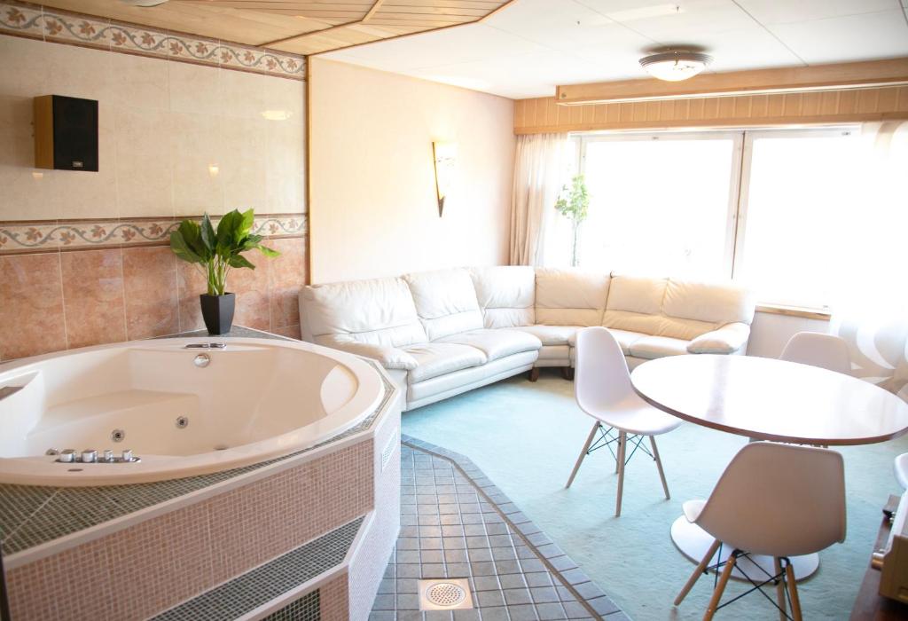 HH Huoneistot Suite في فورسا: غرفة معيشة مع حوض استحمام وأريكة