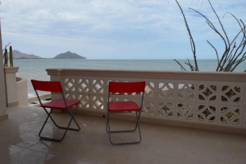 Duas cadeiras vermelhas sentadas numa varanda com vista para o oceano em Steps to the BEACH Las Palmas Condo # 1 em San Felipe