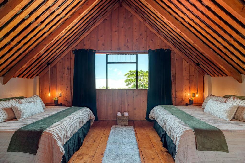 two beds in a room with a large window at The Red Door Mountain Cabin 