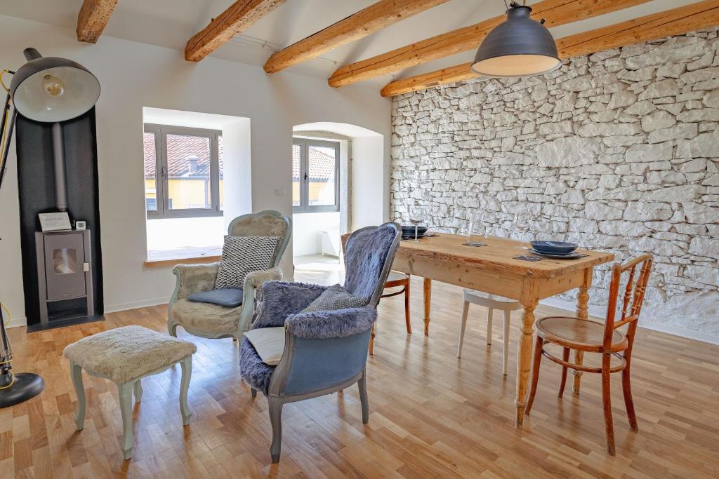 d'une salle à manger avec une table, des chaises et un mur en pierre. dans l'établissement CASA OPICINA - Elegante appartamento in VILLA CARSICA, à Villa Opicina