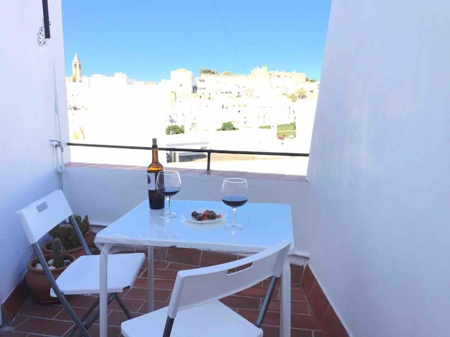 贝赫尔-德拉弗龙特拉Casa Arena y Sal en pleno casco antiguo de Vejer的阳台上的一张白色桌子和两杯葡萄酒