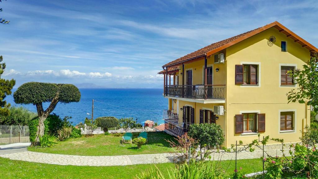 a yellow house with a view of the ocean at Eleni's Apartments & Studios 1 in Achílleion