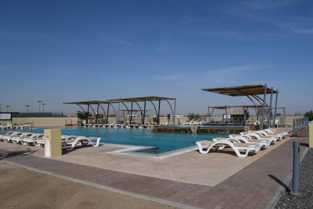 a pool with a bunch of white chairs and water at Casa Sunrise - El Dorado Ranch Vacation Rental Home in San Felipe