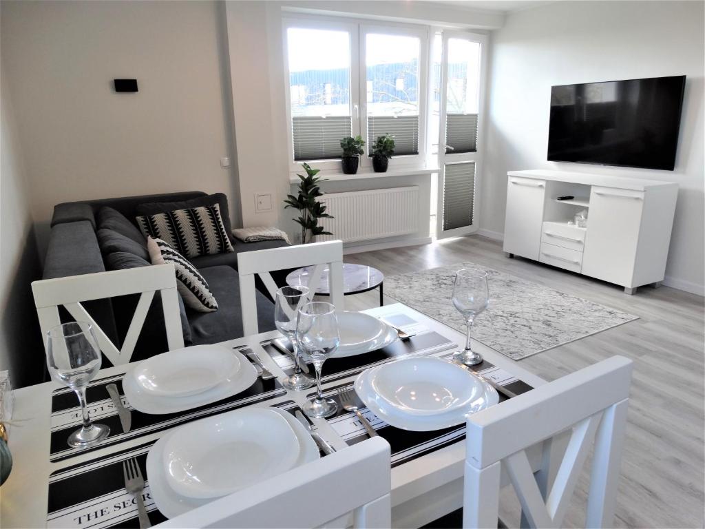 a living room with a dining room table with white plates at Apartament Centrum Świnoujście in Świnoujście