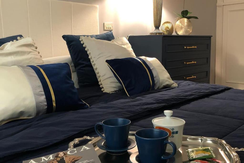 uma cama com almofadas azuis e brancas e uma bandeja com chávenas em Rosymarty Apartment-vicino Firenze em Prato