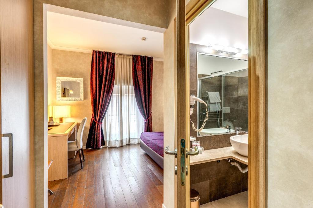 een badkamer met een bed, een wastafel en een spiegel bij Roma Boutique Hotel in Rome